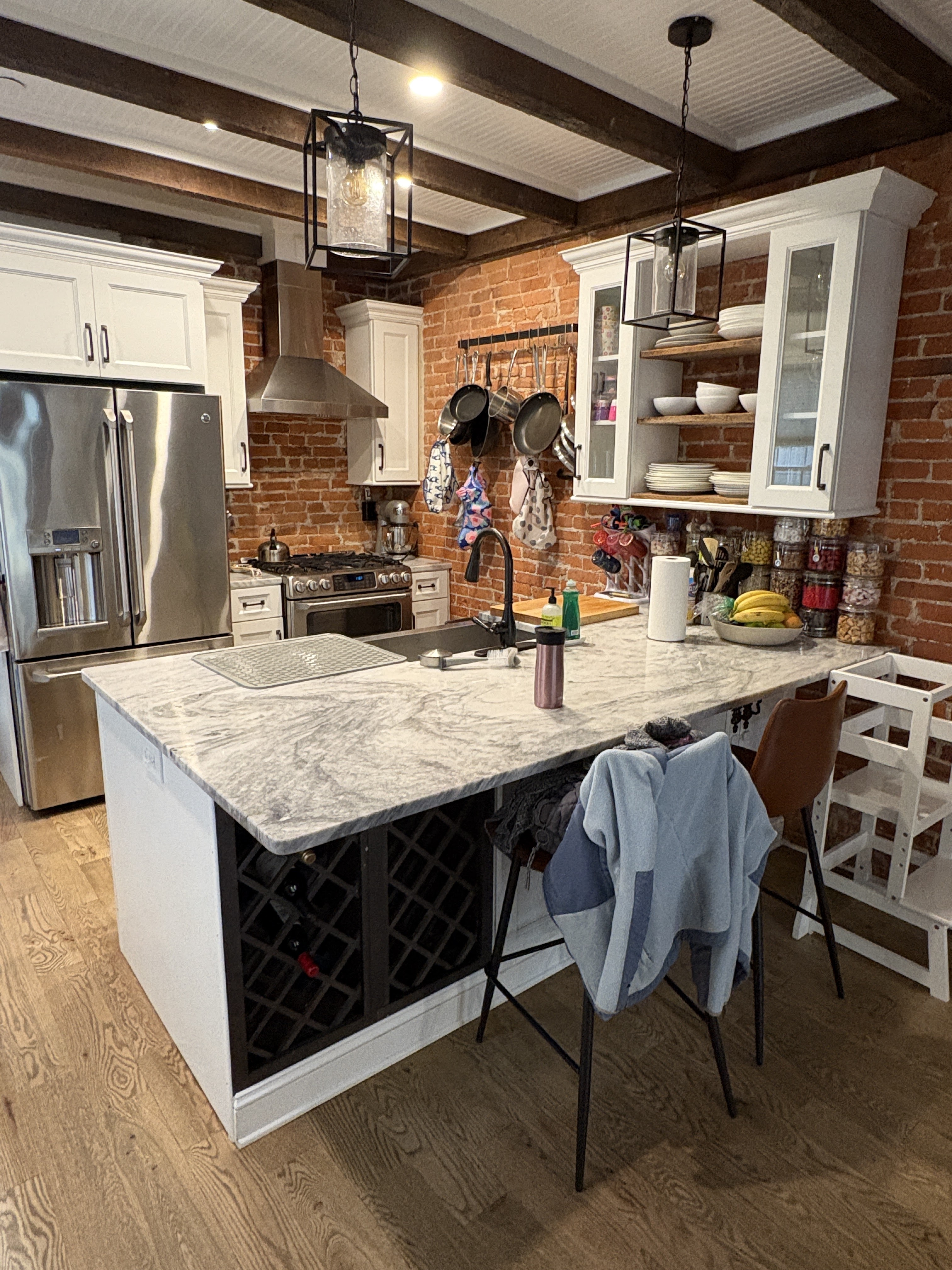 Kitchen with exposed brick, beam ceiling, and marble island